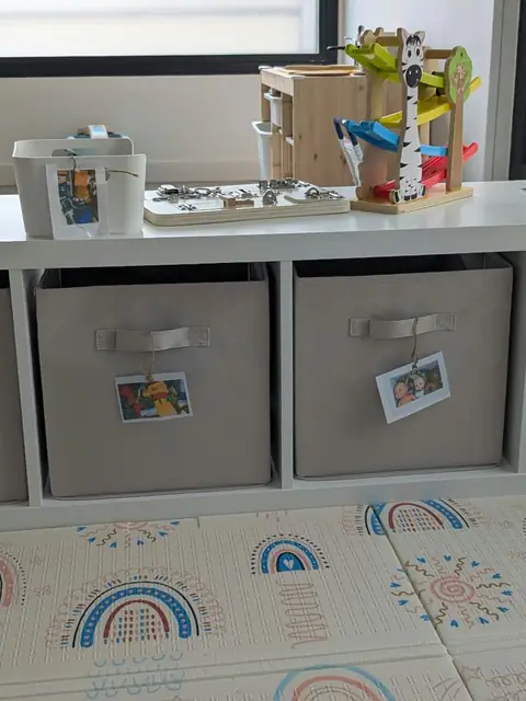 Meuble de rangement avec bacs &eacute;tiquet&eacute;s par des photos, circuit en bois et tapis