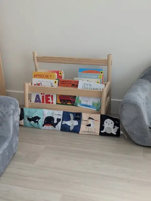 Coin lecture avec &eacute;tag&egrave;re &agrave; livres, livre en tissu et petits fauteuils gris