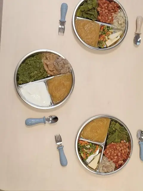 Trois assiettes compartiment&eacute;es en inox et leurs couverts, vus du dessus