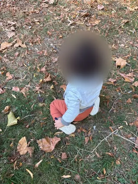 Enfant assis dans l&rsquo;herbe et les feuilles d&rsquo;automne
